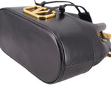 Black mini bucket crossbody bag corner close-up with gold hardware and rounded base