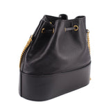Black mini bucket crossbody bag with drawstring top, gold chain trim, rounded base