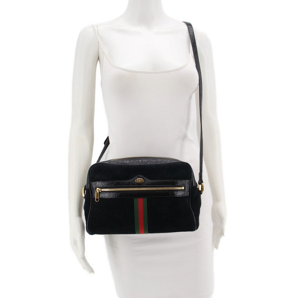 Black suede crossbody bag worn on model with adjustable strap and green-red web stripe