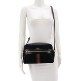 Black suede crossbody bag worn on model with adjustable strap and green-red web stripe