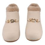 Pair of cream booties with faux shearling lining and gold emblem strap