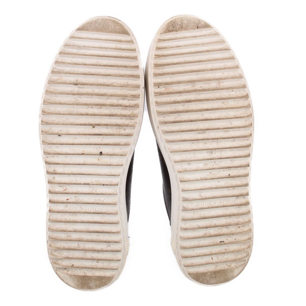White treaded rubber outsole of brown monogram sneakers, bottom view.