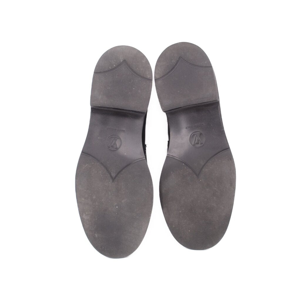 Underside view of black leather loafers with rubber soles