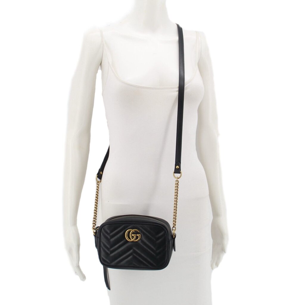 Black GUCCI crossbody bag on a mannequin with gold chain strap over a white outfit