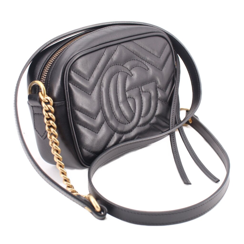 Black quilted leather crossbody bag with embossed GUCCI double-G on front and dangling tag
