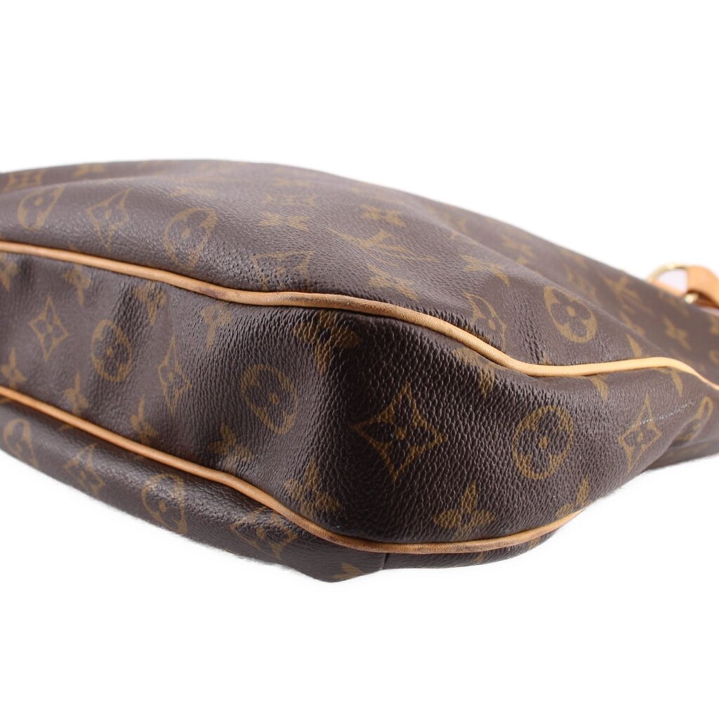 Close-up of monogram tote bag rounded side and seam with tan edge trim on dark brown leather