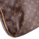 Close-up of monogram tote bag bottom corner with tan edge trim on dark brown patterned leather