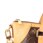 Monogram crossbody bag corner with beige leather patch, zipper track, and lock charm