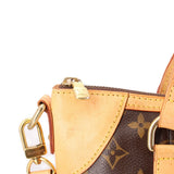 Monogram crossbody bag corner with beige leather patch, zipper track, and lock charm