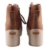 Brown ankle booties with heel tab and side zipper; white outsole edge