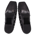Black flats showing textured rubber outsole and silver-tone studs on sides