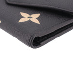 Close-up of black pebbled leather Victorine wallet corner with beige monogram flower