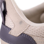 Sneaker detail showing beige suede-like overlay, mesh fabric and dark heel panel