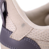 Sneaker detail showing beige suede-like overlay, mesh fabric and dark heel panel