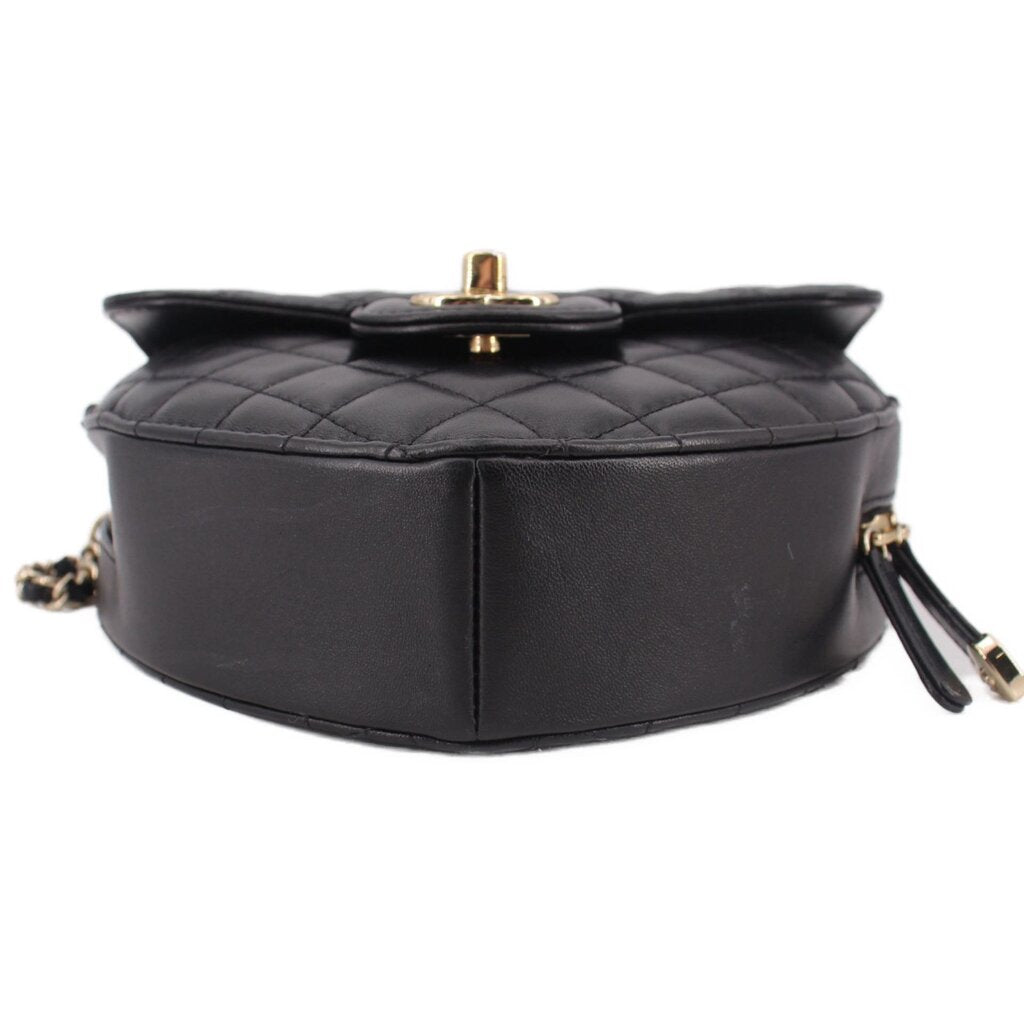 Black quilted heart crossbody bag top view with gold snap hardware and chain.