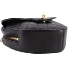 Black quilted heart crossbody bag side view with gold top hardware and chain.