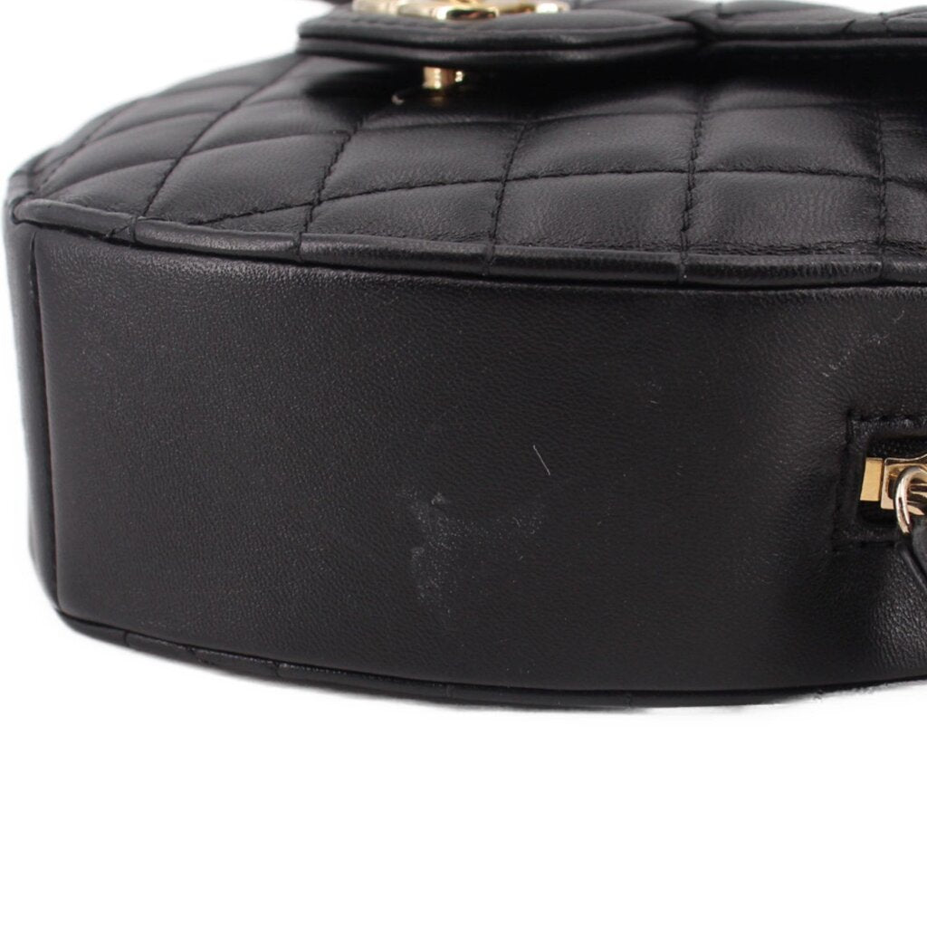 Black quilted heart crossbody bag close-up of smooth leather side panel.