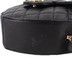 Black quilted heart crossbody bag close-up of smooth leather side panel.