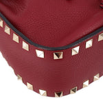 Close-up of red leather bucket edge with Rockstud trim along the bottom