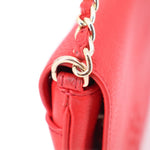 Red leather crossbody bag with metal chain and clasp at strap attachment