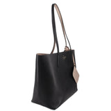 Black reversible tote bag side view with beige lining peeking at handles.
