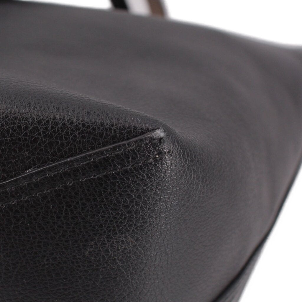 Black reversible tote bag corner close-up with curved seam stitching.