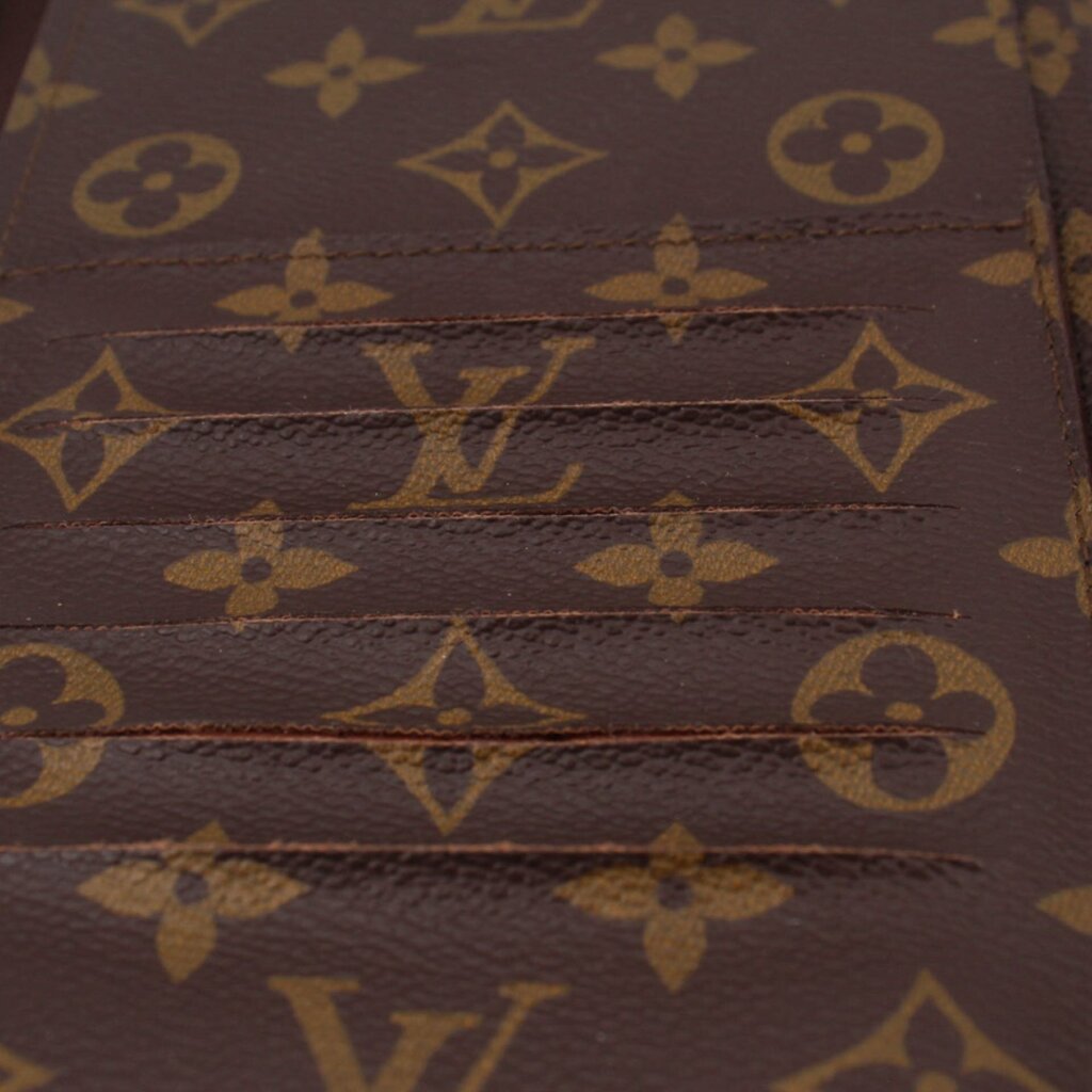 LOUIS VUITTON Voyage organizer wallet close-up of brown monogram canvas texture and stitching.