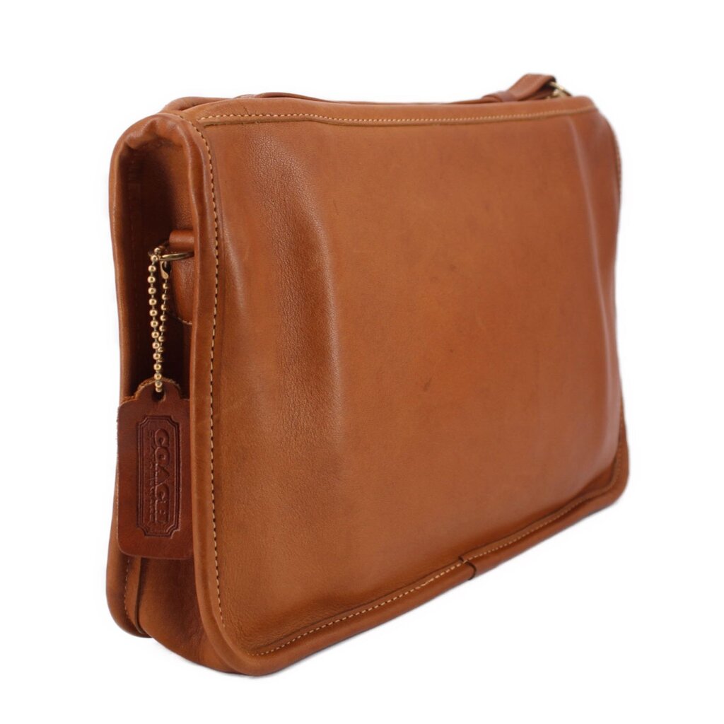 Tan leather clutch bag with shoulder strap, dangling chain detail, top zipper.