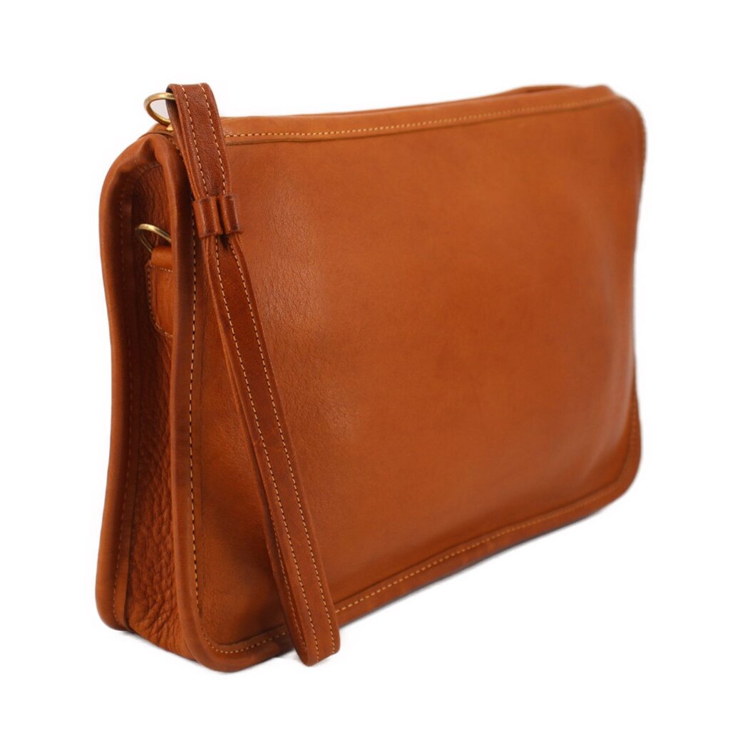 Tan leather clutch bag with hanging strap and top zipper, slim profile.