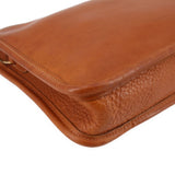 Tan leather clutch corner with stitched edge and smooth curved flap.