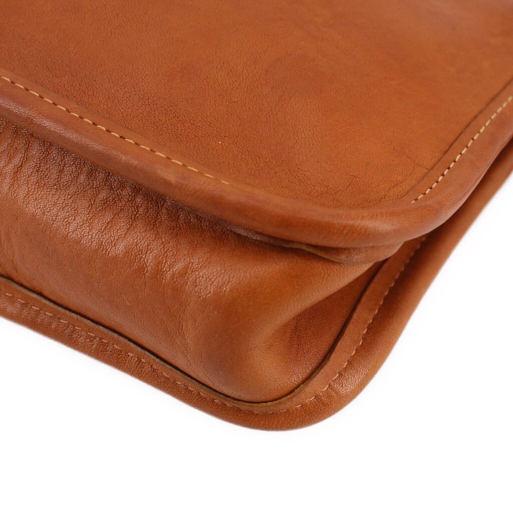 Tan leather clutch corner with double stitching and rounded edge detailing.