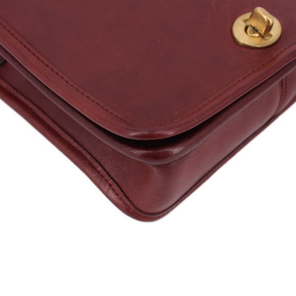 Oxblood leather bag corner with flap seam and brass turn-lock hardware