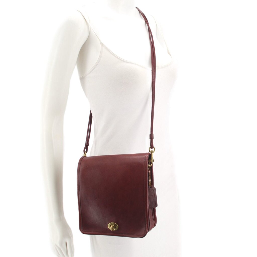Oxblood leather compact crossbody pouch shoulder bag worn on a model