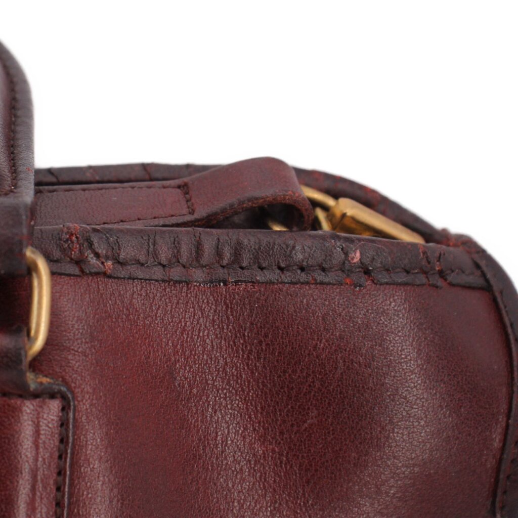 Oxblood leather satchel top view with strap detail and brass ring hardware