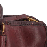 Oxblood leather satchel top view with strap detail and brass ring hardware