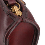 Slim satchel zipper pull with gold-tone hardware and burgundy leather strap