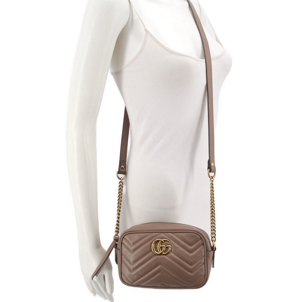 Taupe mini crossbody bag with chain strap on model, small rounded shape