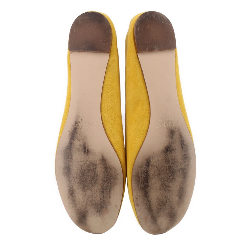 Yellow suede ballet flats with worn leather soles showing speckled texture