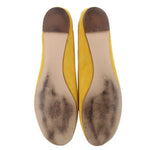 Yellow suede ballet flats with worn leather soles showing speckled texture