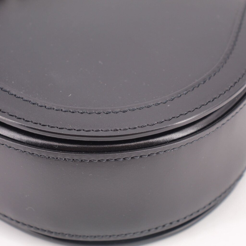 Black leather shoulder bag close-up of curved edge with contrast stitching