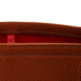 Close-up of brown tote bag seam with red interior lining and stitched edge.