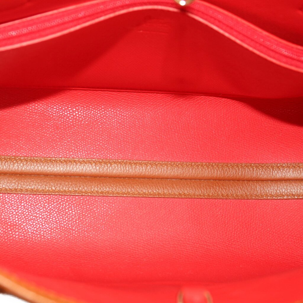 Brown tote bag interior with red lining, visible top opening and textured leather.