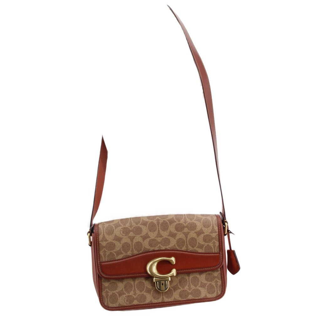 Cognac Coach mini shoulder bag with signature canvas, gold C clasp, and crossbody strap