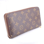 Monogram zip-around wallet side view in brown with repeating gold pattern and zip closure