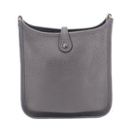 Small crossbody bag front view, textured leather, center snap closure, adjustable dark strap