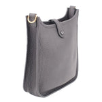 Small crossbody bag side view, textured leather, top loops with gold ring hardware, dark