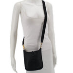 Small crossbody bag on model, dark leather with perforated H logo, adjustable strap, snap top