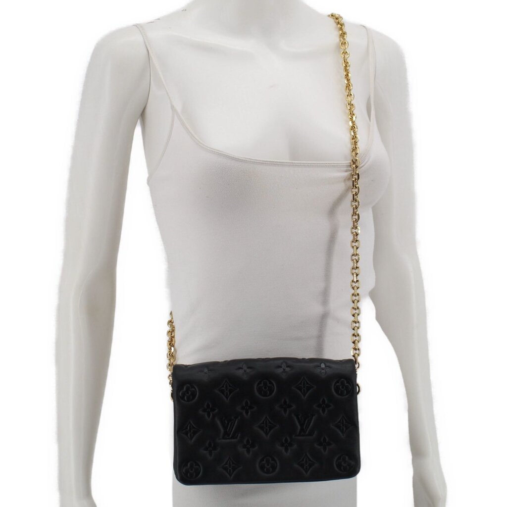 Black embossed monogram crossbody bag worn with gold chain strap