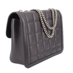 Black quilted shoulder bag with flap and silver-tone chain strap; side angle view.