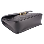 Black shoulder bag with gold-tone clasp and quilted side seams; angled view.